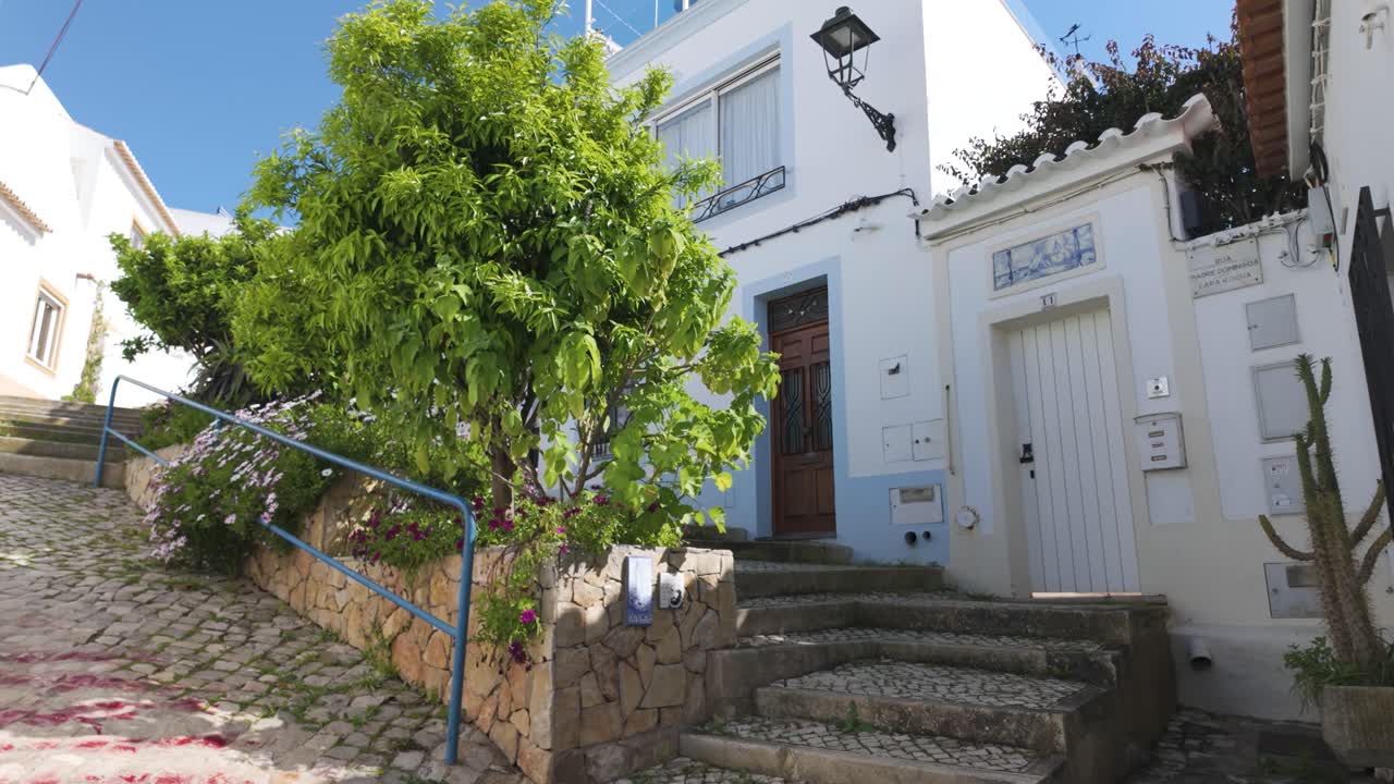 Cobbled stairway with trees and tiled houses in Ferragudo Portugal
