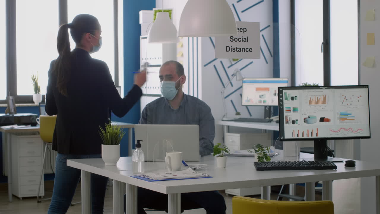 보호 얼굴 마스크를 착용한 프리랜서가 온도계를 사용하여 동료의 온도를 확인합니다.