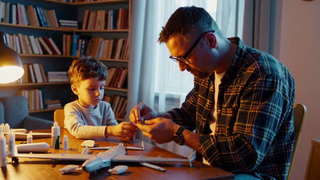 father and son building model airplanes together