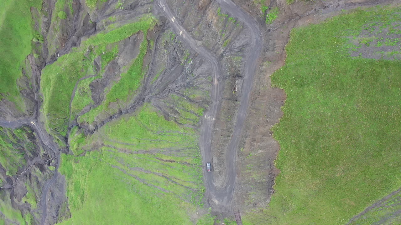 toma cinematográfica de drones en ángulo descendente de un vehículo que conduce por acantilados empinados en el camino a tusheti, uno de los caminos más peligrosos del mundo