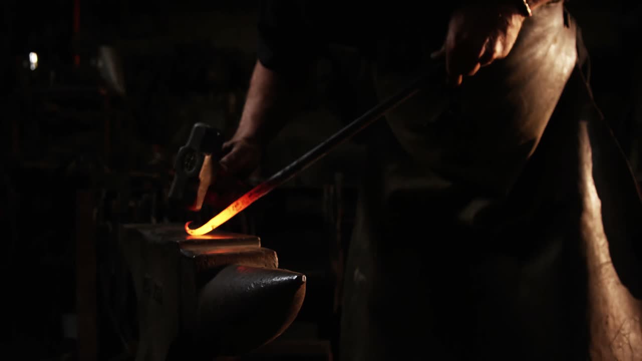 Mid-section of blacksmith working on a iron rod