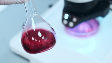 científico mezclando líquido rosado en los frascos de vidrio