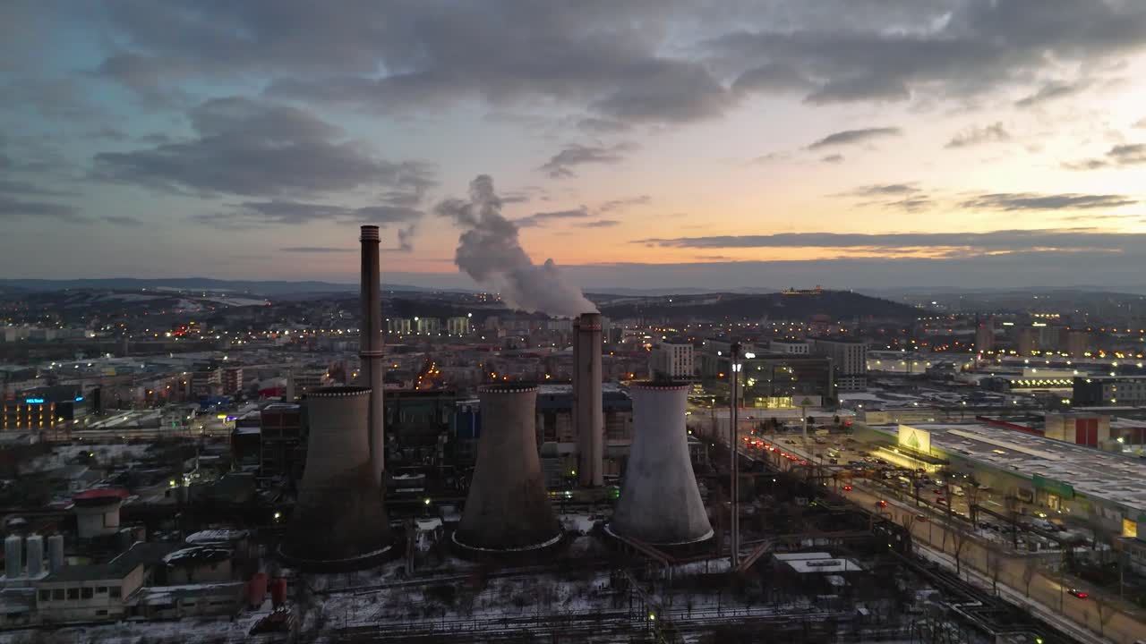 Industrial chimneys emitting smoke over Iași at sunset