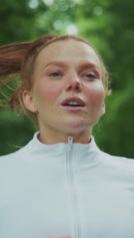 a woman running outdoors with a focused expression: capturing the essence of determination and fitness in a naturally lush environment