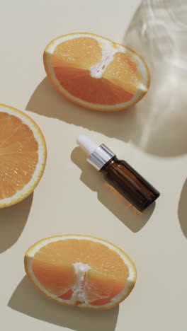 vertical video of make up bottle with pipette, orange slices and copy space on white background