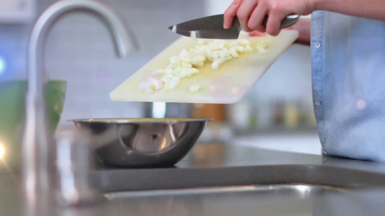Animazione di luce sul busto di un uomo che cucina usando un coltello e un tagliere in cucina.