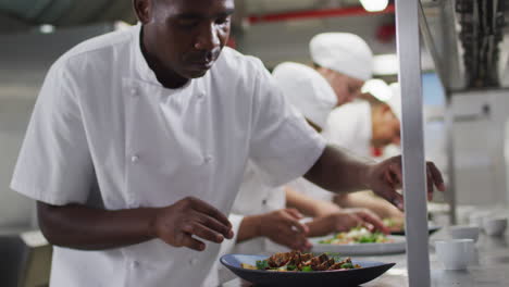 grupo diverso de chefs adornando platos en la cocina del restaurante