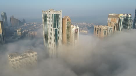 Nebel-In-Den-Vereinigten-Arabischen-Emiraten:-Blick-Von-Oben-Auf-Dichten-Nebel-über-Dem-Al-Majaz-Gebiet-Von-Sharjah,-Skyline-Von-Sharjah-Im-Wintermorgennebel,-Vereinigte-Arabische-Emirate,-4K-Drohnenaufnahmen