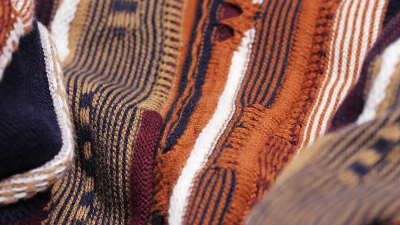 A warm striped knit sweater reveals stitches and folds as the camera pans slowly in selective focus
