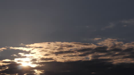 Time-lapse,-Rays-of-Golden-sun-shining-through-dramatic-dark-storm-clouds-moving-in-different-directions