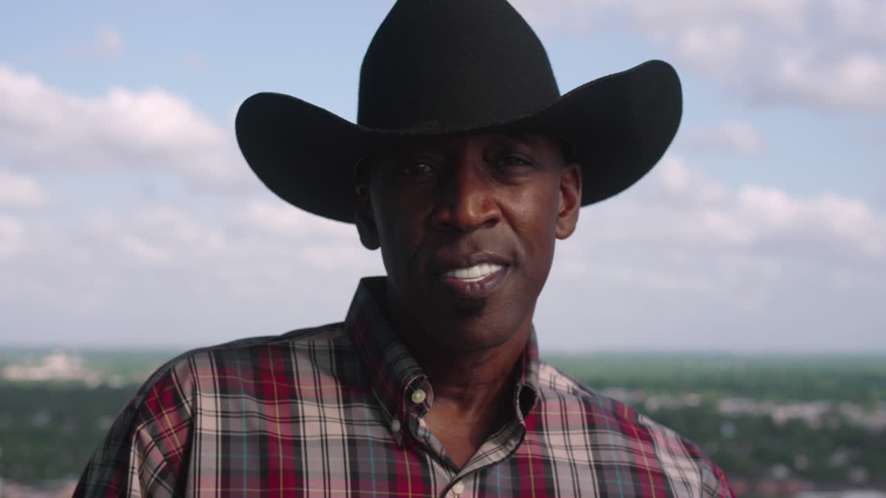 retrato de un hombre negro con sombrero de vaquero sonriendo