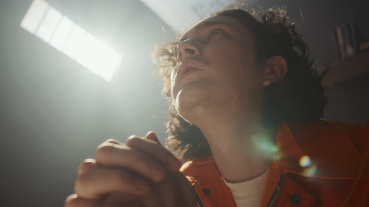Close-Up of Young Prisoner Saying Prayer with Hands Clasped