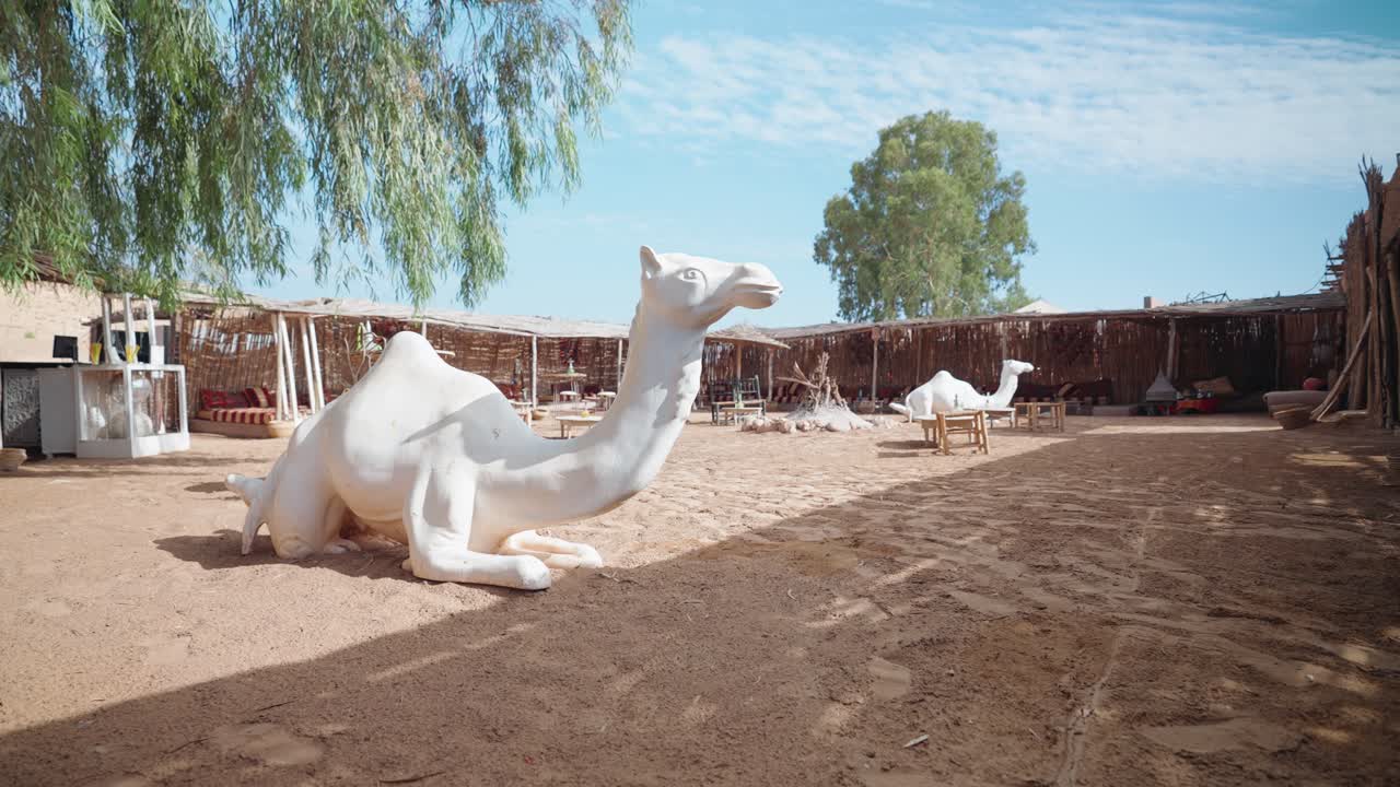 vista de amplio ángulo que muestra una escultura surrealista de camello blanco en la inmensidad de un desierto artificial