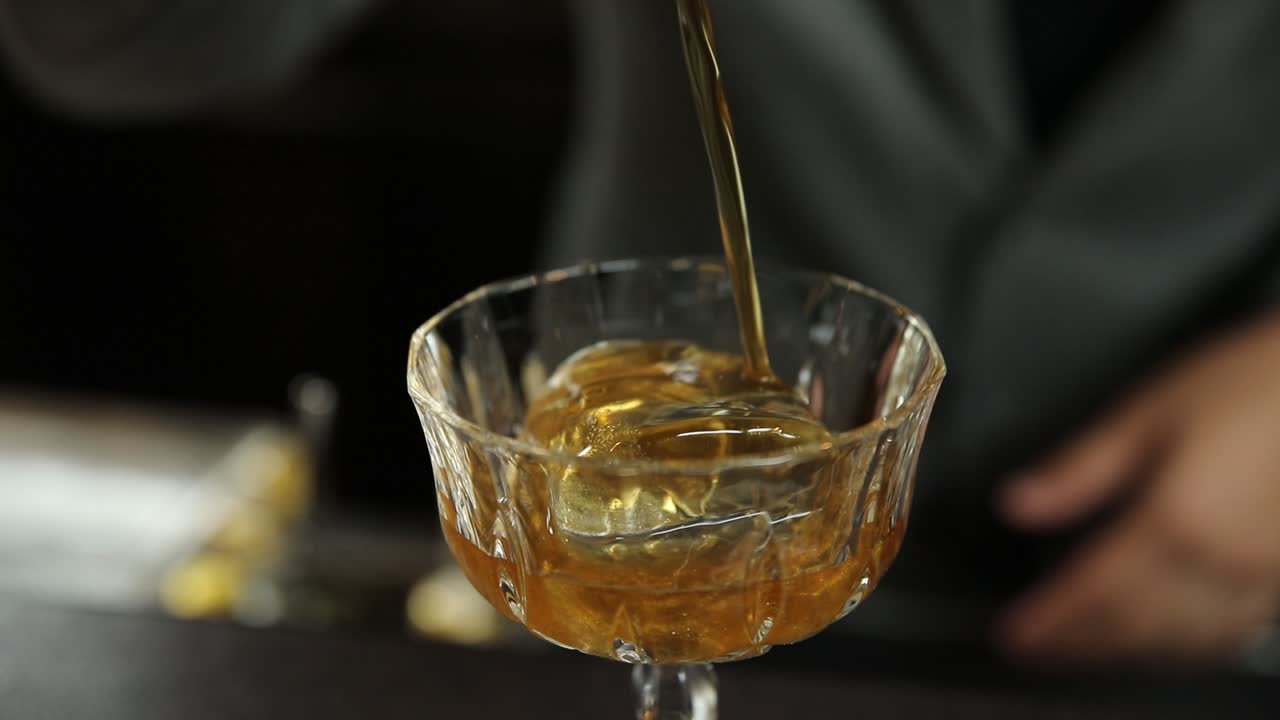 El camarero vertiendo un cóctel en el vaso.