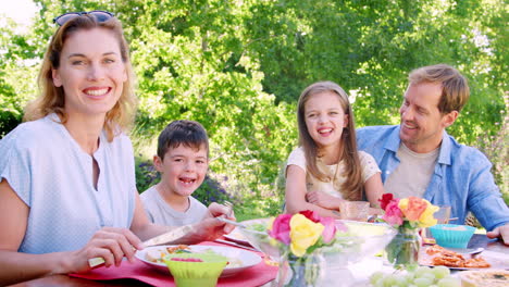 parents and kids having lunch in the garden look to camera