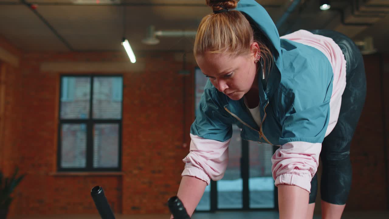 Healthy caucasian woman exercising workout on stationary cycling machine bike in gym slow motion