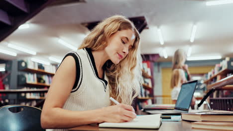 woman studying in a library with laptop and books