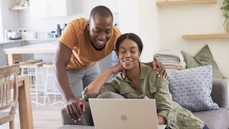 A-diverse-couple-is-enjoying-time-with-a-laptop-on-the-couch-at-home