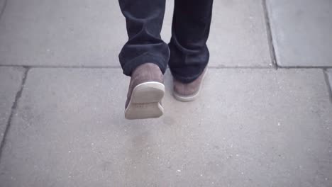 shot-of-the-feet-of-a-man-walking-on-a-street-pavement