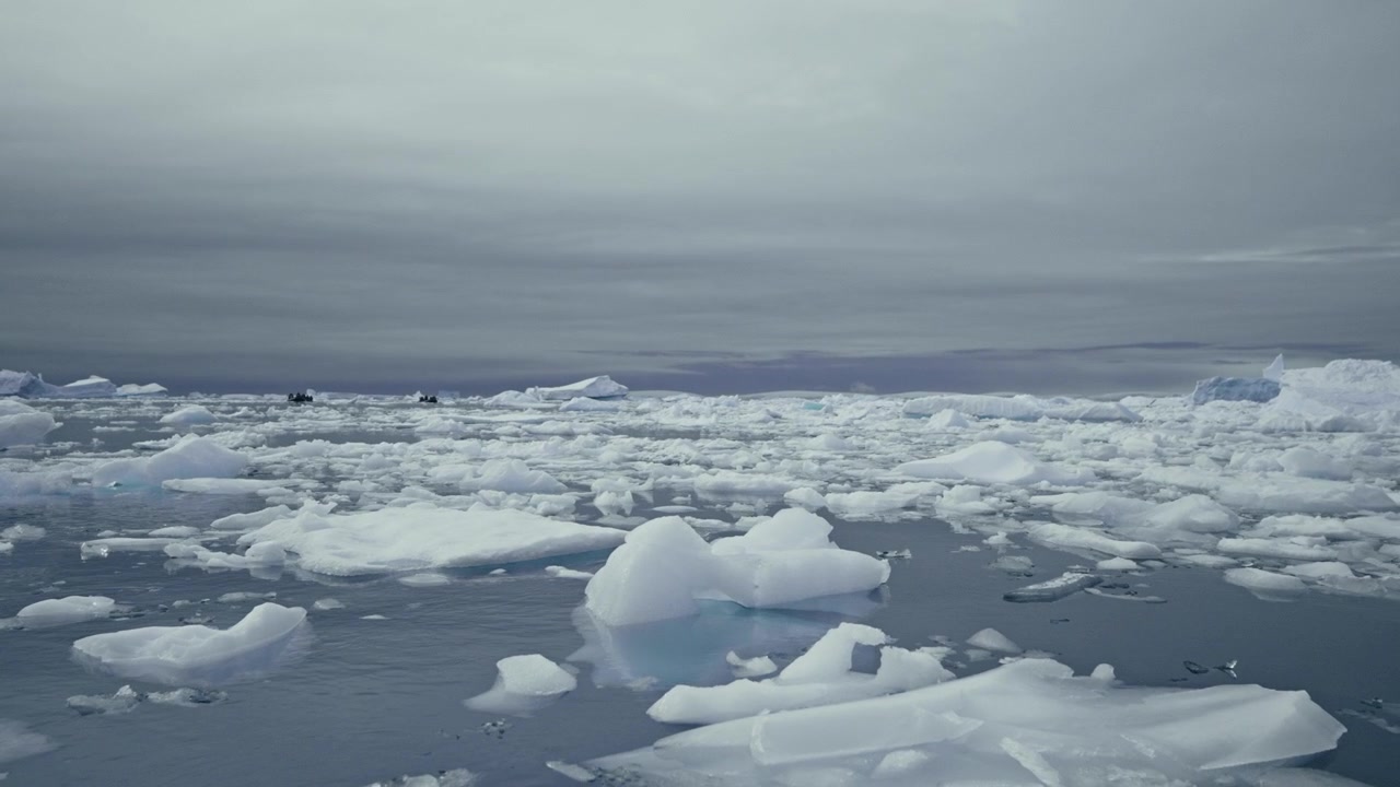 Dense field of floating ice floes and icebergs across Antarctic Southern Ocean under grey overcast sky