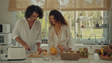 couple cooking fresh fruit salad in a tropical kitchen