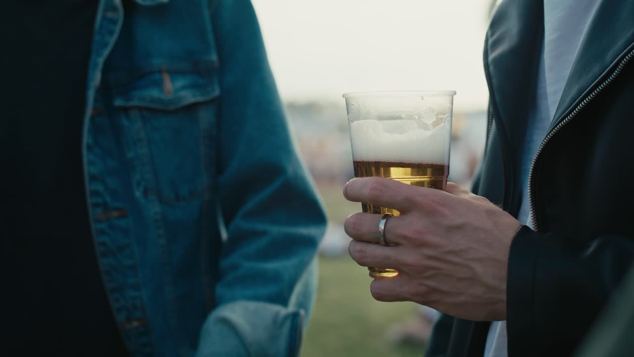 primer plano de un hombre irreconocible sosteniendo una taza desechable con cerveza.
