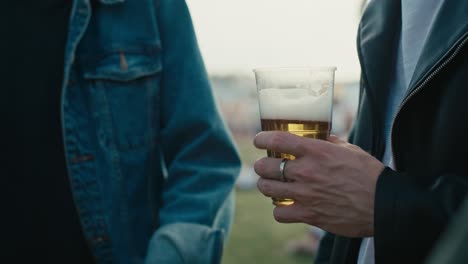 Close-up-of-unrecognizable-man-holding-a-disposable-cup-with-beer.