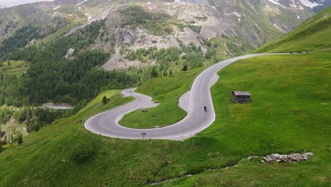 winding alpine road unfolds through high mountains as cyclist glides down alone