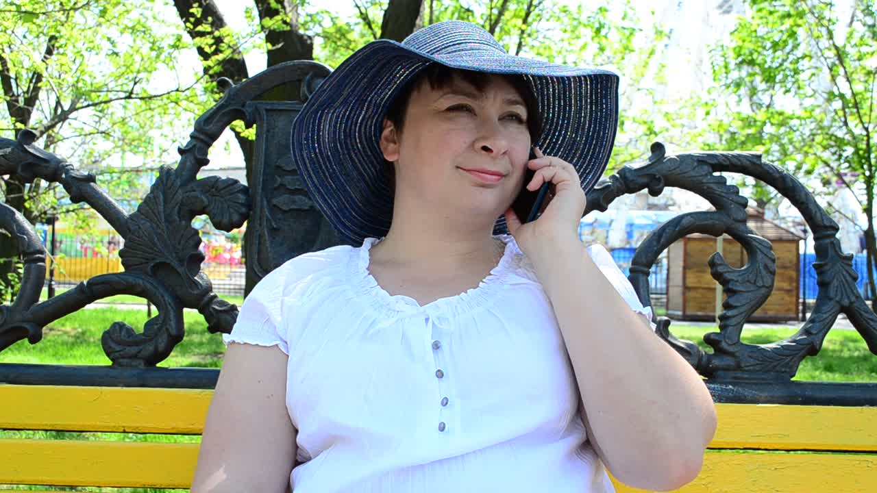 公園で電話する少女。公園のベンチ