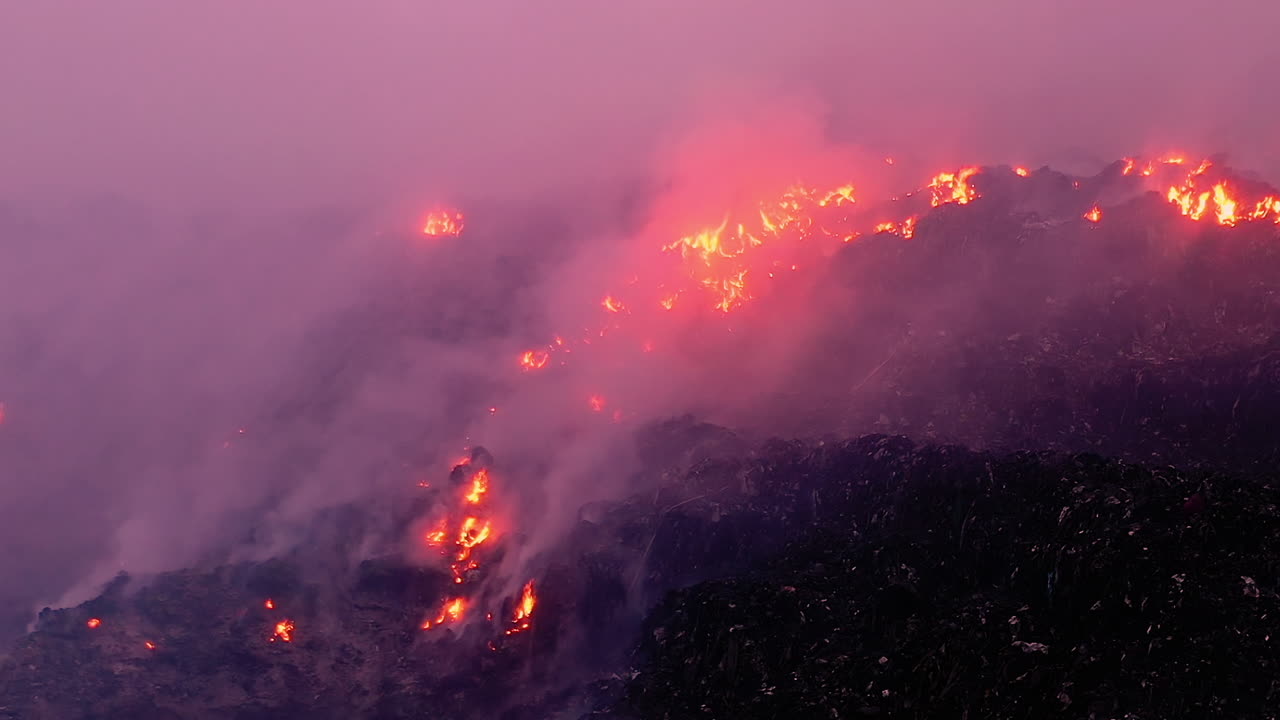 Aerial view towards a wildfire raging and smoke rising, on a dark evening, in Pantanal, Brazil, South America - dolly, drone shot