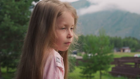 una niña con cabello rubio se para en el patio de un hotel de montaña