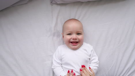 a newborn baby lying on the bed, looking into the camera and around on a white bed sheet, view from above. infant knows the world, top view