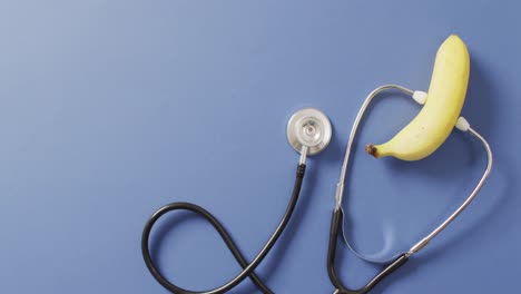 video of close up of stethoscope with banana on blue background