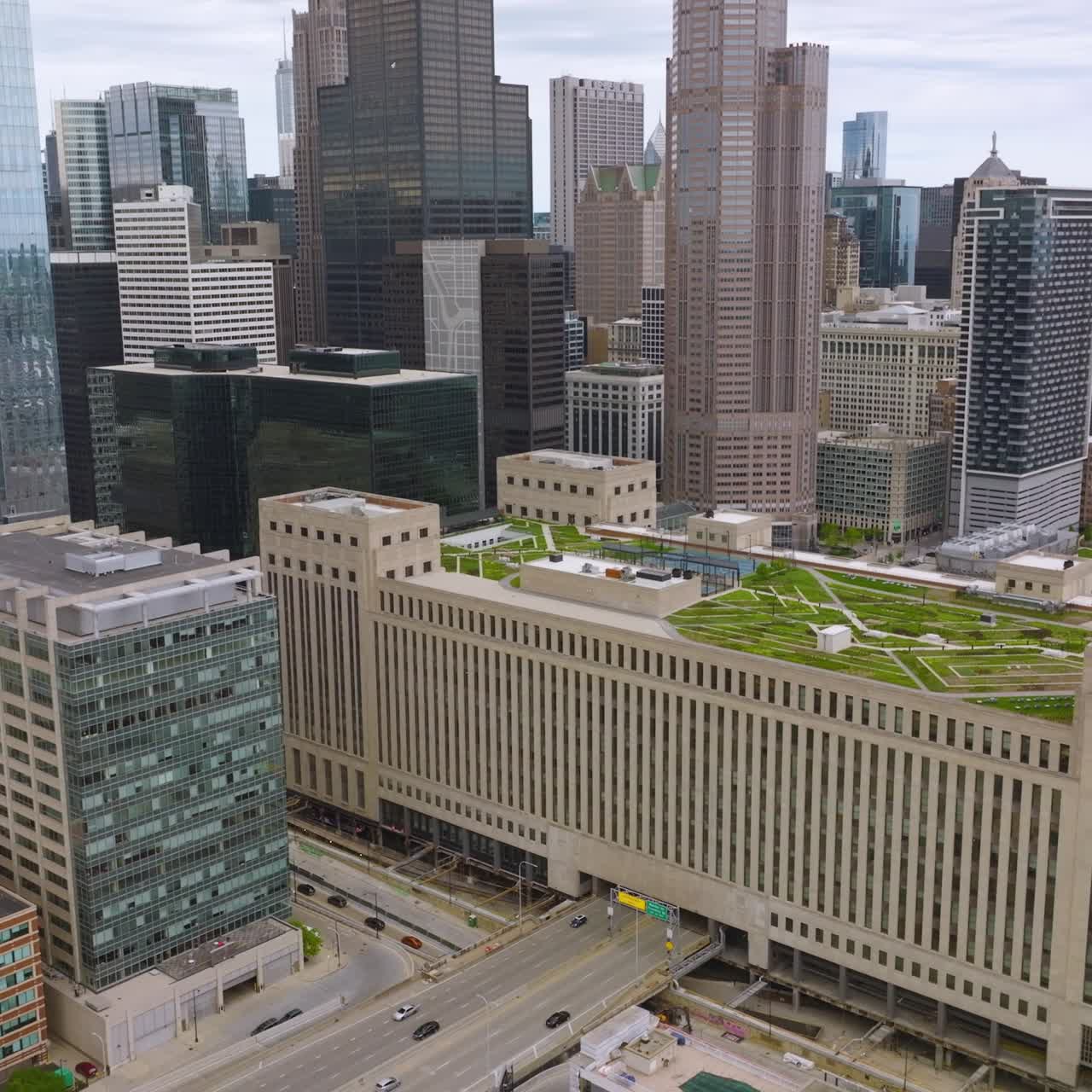 Multi-lane road passing through the multi-storied building with green zone on top. Fascinating architecture of Chicago, Illinois, USA from aerial view