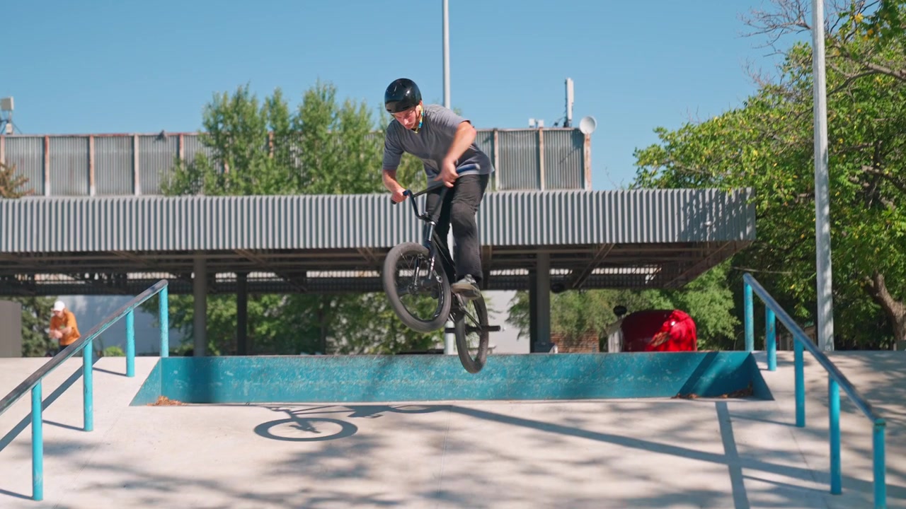 Giovane uomo in bici BMX che esegue un trick di salto in uno skatepark