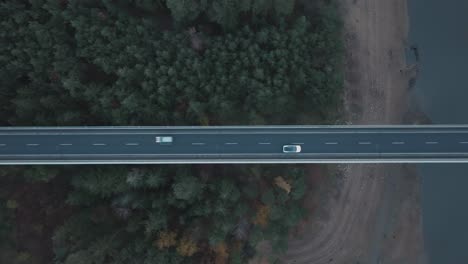 Luftaufnahme-Von-Oben-Nach-Unten,-Weißes-Auto,-Das-Sich-Auf-Der-Brücke-über-Wald-Und-Fluss-Bewegt