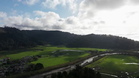 Beautiful-drone-aerial-view-of-a-wide-open-green-field-with-clouds-passing-above