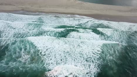 drone video of ocean opening to river mouth and river with mountains in the distance