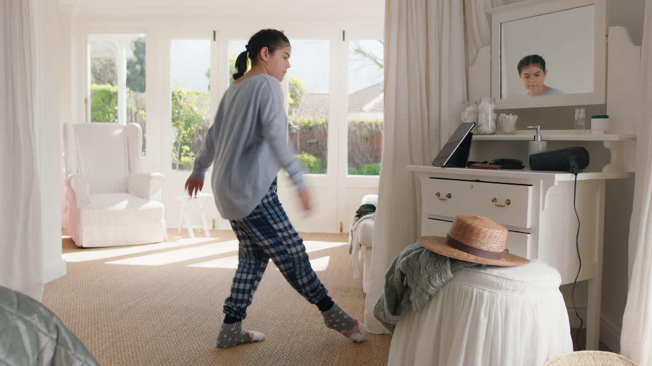 행복한 십대 소녀는 침실에서 발레 춤을 연습하고 리허설하고 주말 아침에 파자마를 입고 재미있는 춤을 추고 있습니다.