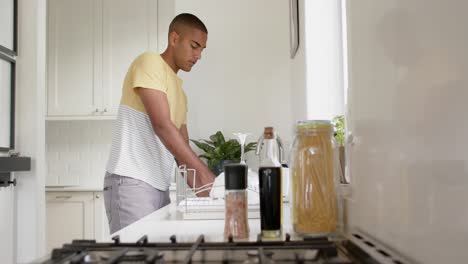 hombre biracial lavando platos en una cocina brillante, cámara lenta