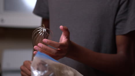 young african american man holds a whisk and is ready to help stir ingredients together