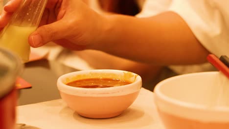 hand pouring sauce into a small bowl