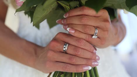 close up shot of bride hands with rings and manicure, holding bouquet