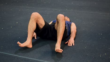 a still shot of a guy in a gymnastics gym doing hip raises from a diagonal view