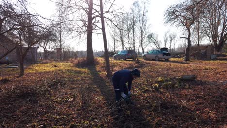 gardener remove old tree branches with electric chainsaw at cottage yard