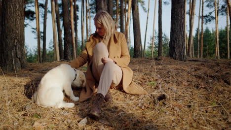 cute middle-aged woman relaxing in the forest with a golden retriever puppy