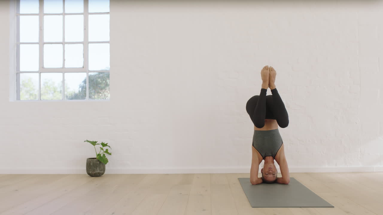 운동 매트에서 아름다운 신체 훈련을 하는 스튜디오에서 운동하는 피트니스 라이프스타일을 즐기는 헤드스탠드 포즈를 연습하는 건강한 요가 여성