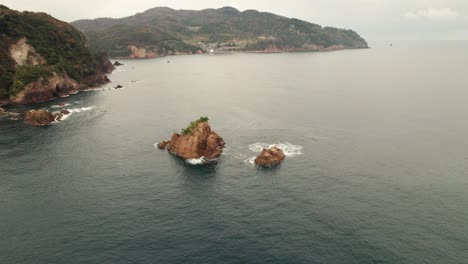 Pequeños-Islotes-De-La-Playa-De-Kyotango-Viajan-Al-Mar-Japonés-Destino-Aéreo-Drone-Paisaje-De-Agua-Azul-Limpia-Y-Cordillera-En-Kansai,-Costa-De-Arena-Blanca-De-Kyoto