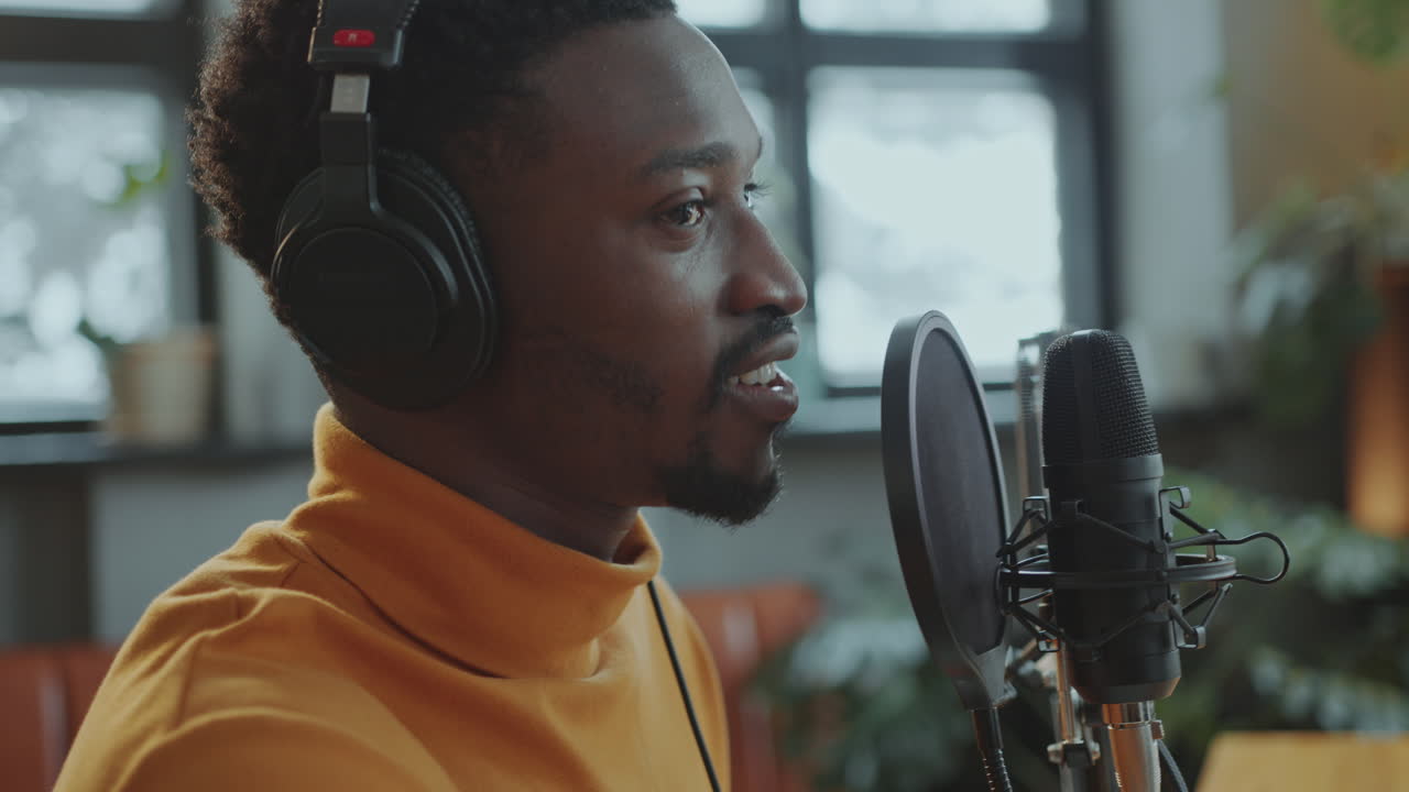 Black Blogger in Headphones Hosting Podcast Interview in Studio