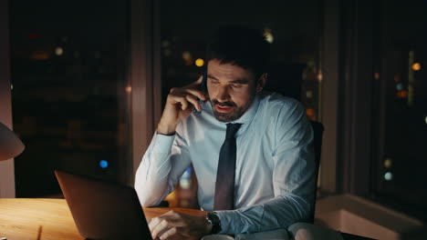 tired entrepreneur calling partners sitting office desk late evening close up.